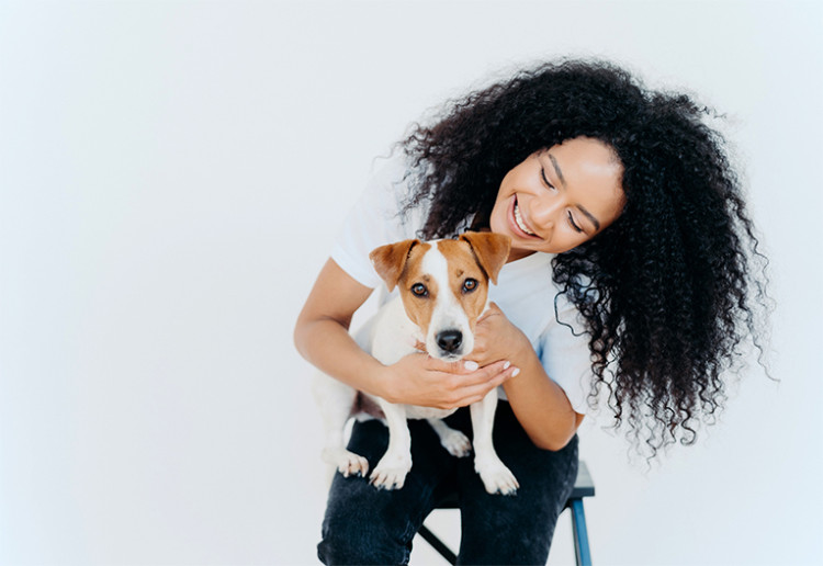 Smiling woman holding her dog on a stool.