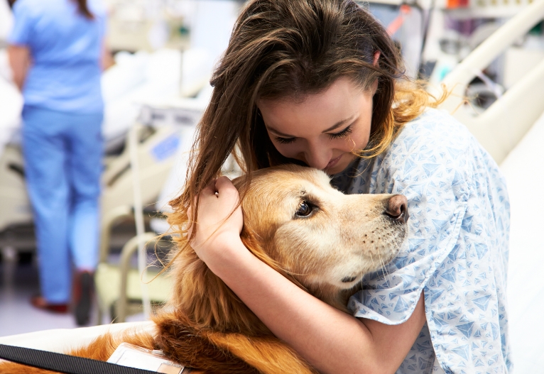 Woman hugging a therapy dog in hospital.