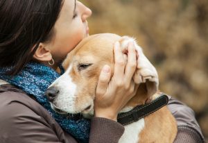 Woman hugs a sad dog.