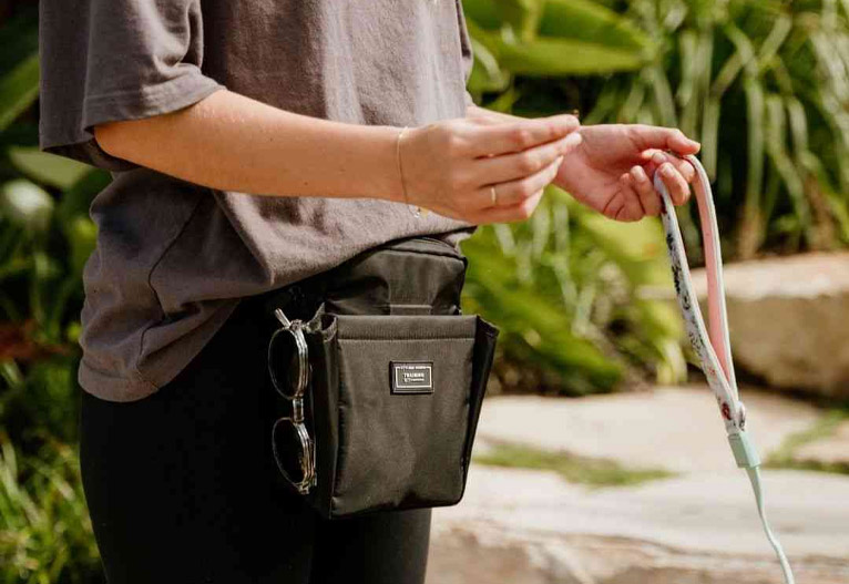 Woman wearing the Stylish Hound dog treat bag in black.