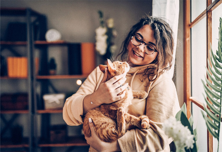 Woman holding a cat near a window.